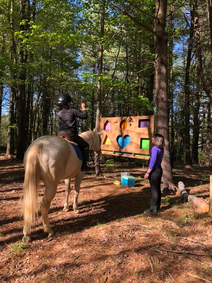 A rider on a horse putting pieces into a puzzle on the sensory trail course